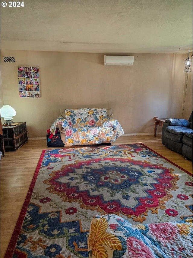 bedroom with hardwood / wood-style floors, a wall mounted AC, and a textured ceiling