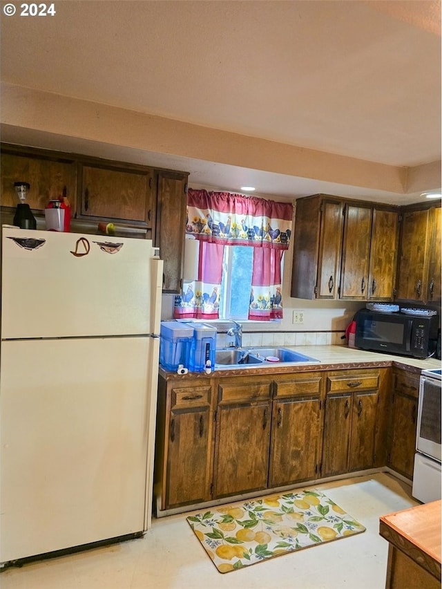 kitchen featuring sink, white appliances, and dark brown cabinets