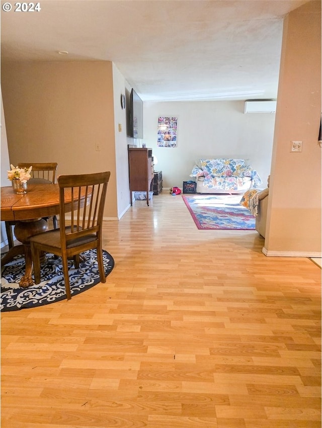 dining space with a wall mounted air conditioner and light hardwood / wood-style flooring