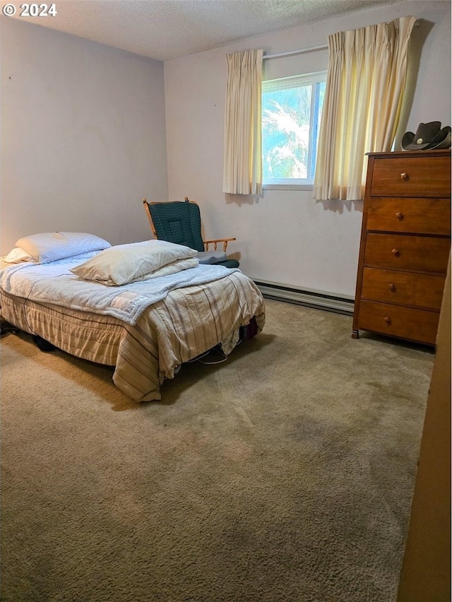 carpeted bedroom with a baseboard heating unit and a textured ceiling