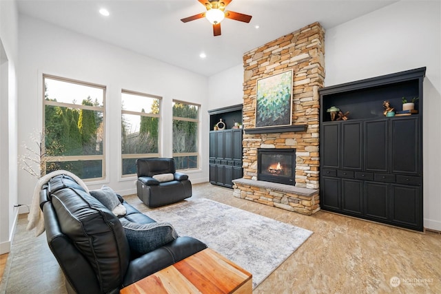 living room featuring ceiling fan and a stone fireplace