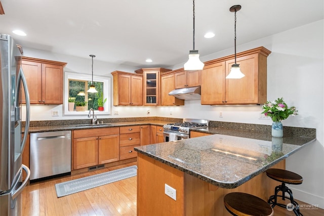 kitchen featuring sink, appliances with stainless steel finishes, dark stone countertops, hanging light fixtures, and kitchen peninsula