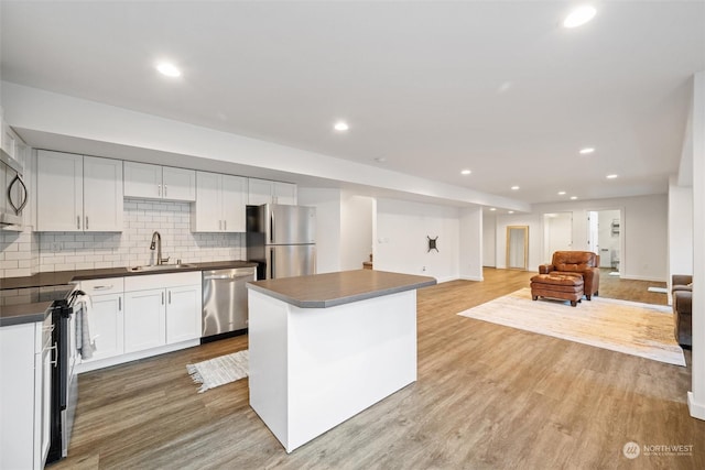 kitchen featuring sink, stainless steel appliances, a center island, white cabinets, and light wood-type flooring