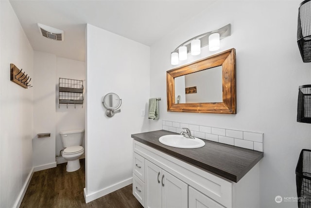 bathroom with hardwood / wood-style flooring, toilet, vanity, and decorative backsplash