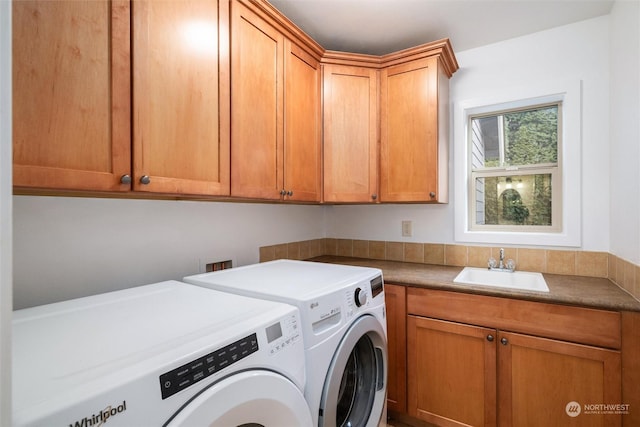 laundry room featuring sink, washer and clothes dryer, and cabinets