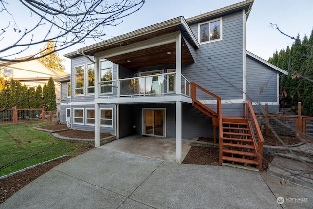 rear view of house featuring a balcony and a lawn