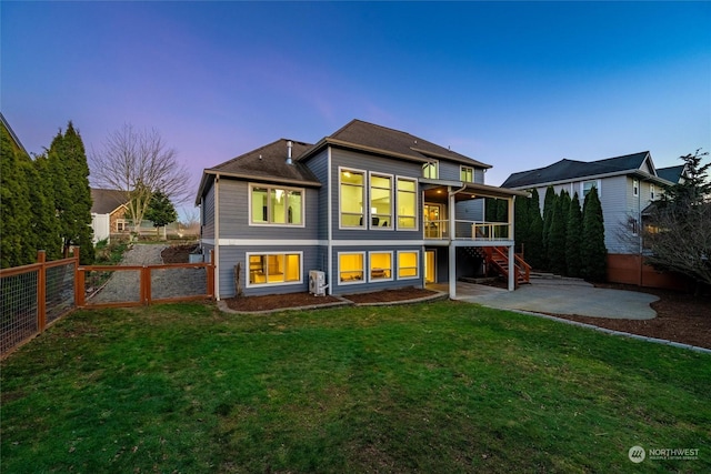 back house at dusk featuring a yard and a patio area