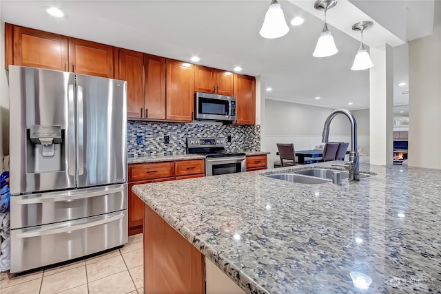 kitchen with sink, hanging light fixtures, appliances with stainless steel finishes, light stone countertops, and decorative backsplash