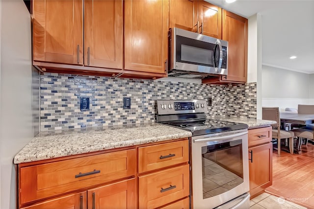 kitchen featuring tasteful backsplash, crown molding, appliances with stainless steel finishes, and light stone counters