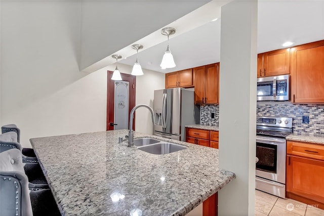 kitchen with light stone counters, a kitchen bar, an island with sink, and appliances with stainless steel finishes