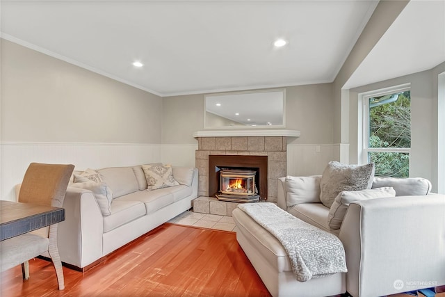 living room with crown molding, a tiled fireplace, and hardwood / wood-style floors