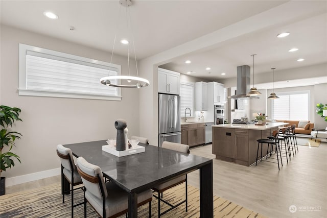 dining area with sink, light hardwood / wood-style flooring, and a chandelier