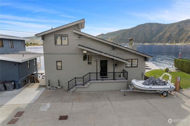 rear view of house featuring a water and mountain view