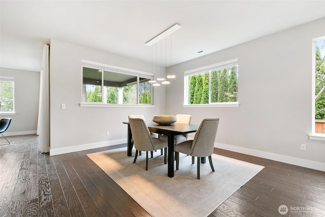 dining room with dark wood-style flooring, a healthy amount of sunlight, and visible vents