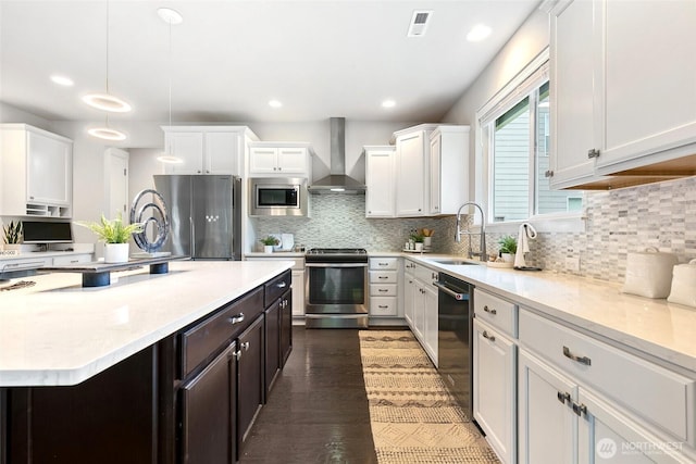 kitchen with stainless steel appliances, a sink, white cabinetry, wall chimney range hood, and decorative backsplash