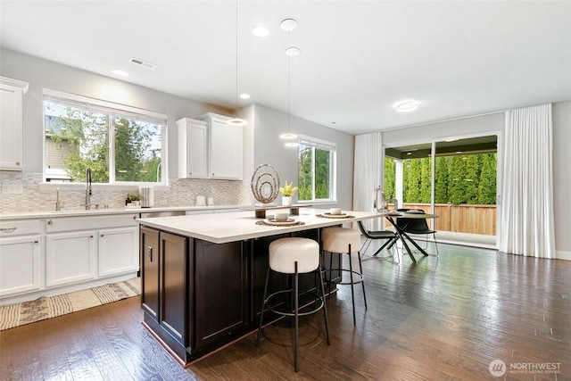 kitchen with a breakfast bar area, light countertops, visible vents, backsplash, and a sink