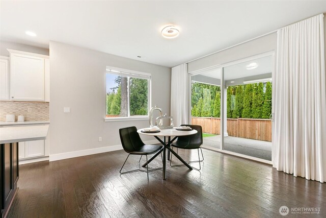 dining area with baseboards and dark wood finished floors