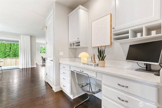 office space featuring dark wood-type flooring, built in desk, and baseboards