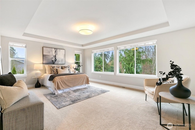 bedroom featuring baseboards, a tray ceiling, and light colored carpet