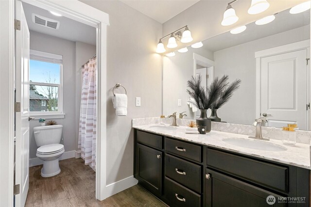 bathroom with double vanity, visible vents, a sink, and wood finished floors