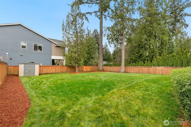 view of yard featuring a storage shed, a fenced backyard, and an outbuilding