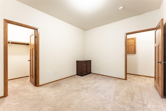 unfurnished bedroom with light colored carpet, a spacious closet, and a closet