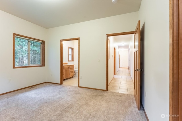 unfurnished bedroom with ensuite bathroom and light colored carpet