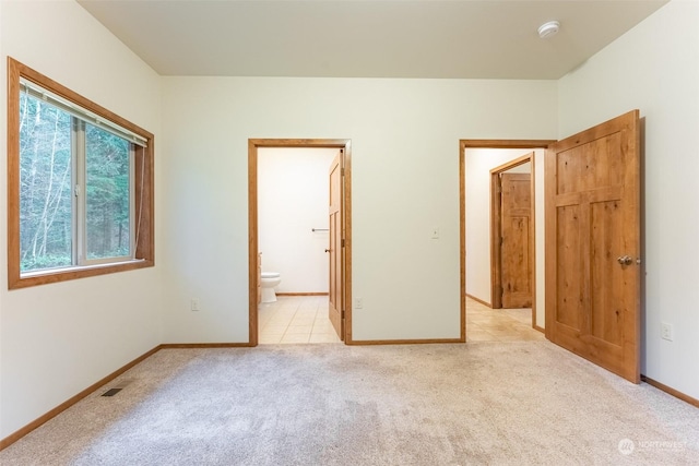 unfurnished bedroom featuring connected bathroom and light colored carpet