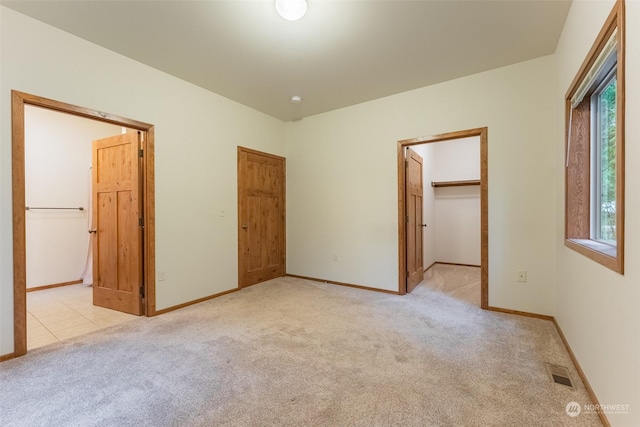 unfurnished bedroom featuring a spacious closet and light carpet