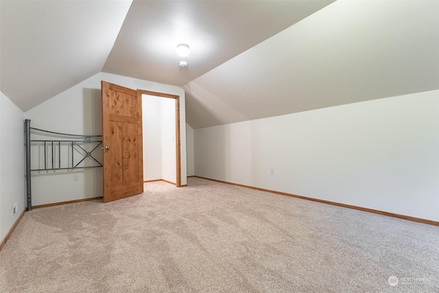 bonus room with lofted ceiling and light carpet