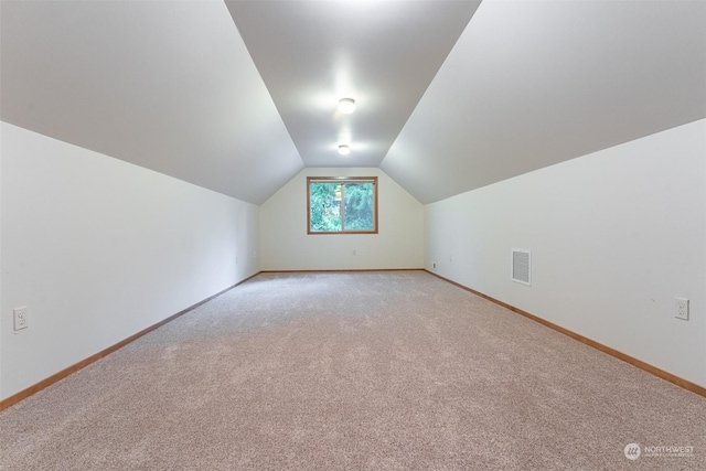 bonus room with vaulted ceiling and light colored carpet