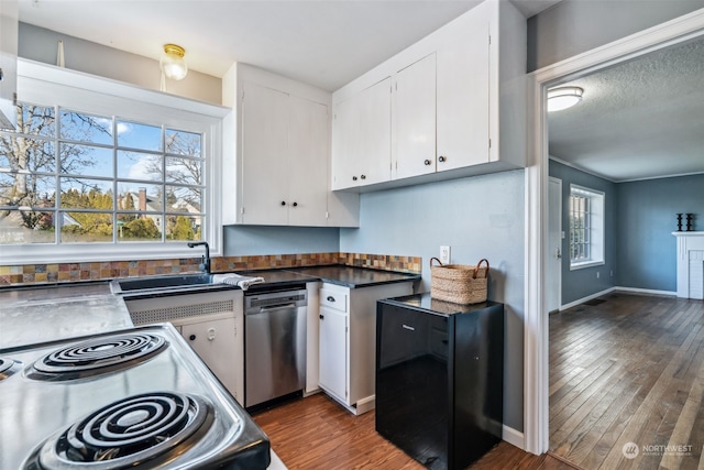 kitchen featuring fridge, stainless steel dishwasher, range with electric stovetop, and white cabinets