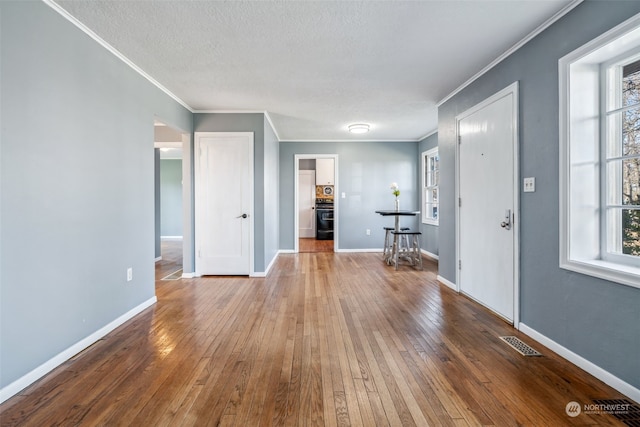 interior space with hardwood / wood-style floors, ornamental molding, and a textured ceiling