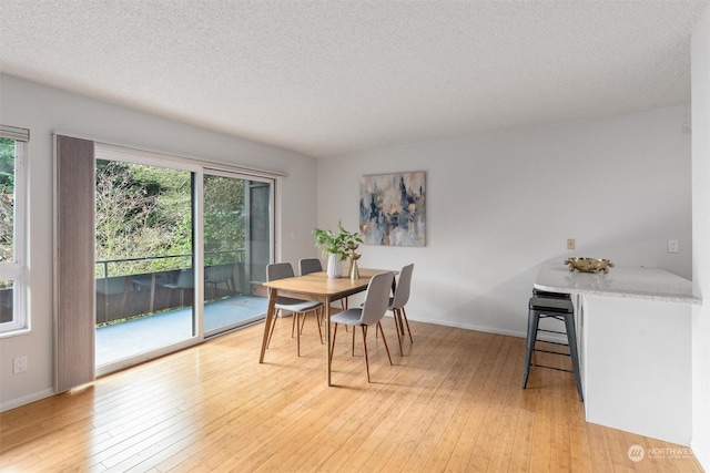 dining area with light hardwood / wood-style floors and a textured ceiling