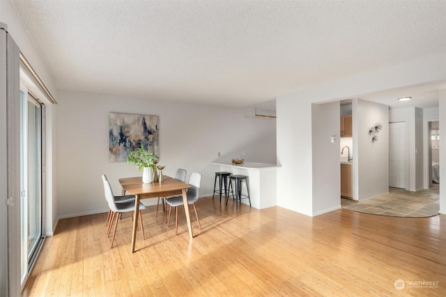 dining area featuring sink, light hardwood / wood-style flooring, and a textured ceiling