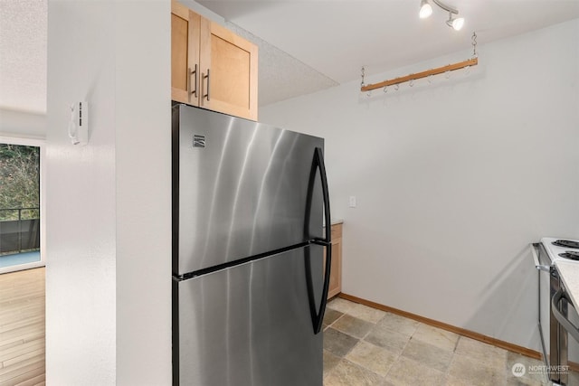 kitchen with stainless steel refrigerator, light brown cabinetry, electric stove, and a textured ceiling