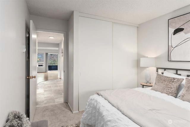 bedroom featuring light carpet, a closet, and a textured ceiling