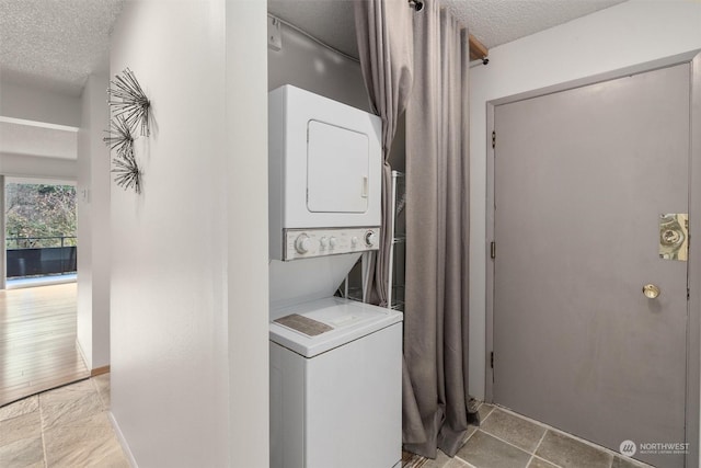 laundry area featuring a textured ceiling and stacked washing maching and dryer