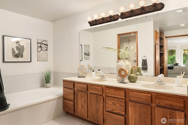 full bathroom featuring tile patterned flooring, a wainscoted wall, a garden tub, and a sink