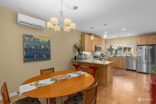 kitchen featuring an AC wall unit, appliances with stainless steel finishes, kitchen peninsula, a notable chandelier, and pendant lighting