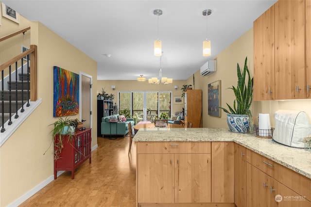 kitchen with a wall mounted air conditioner, a chandelier, kitchen peninsula, pendant lighting, and light stone countertops