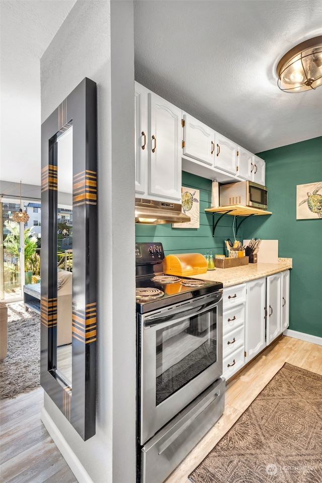 kitchen with stainless steel range with electric cooktop, white cabinetry, a textured ceiling, hanging light fixtures, and light hardwood / wood-style flooring