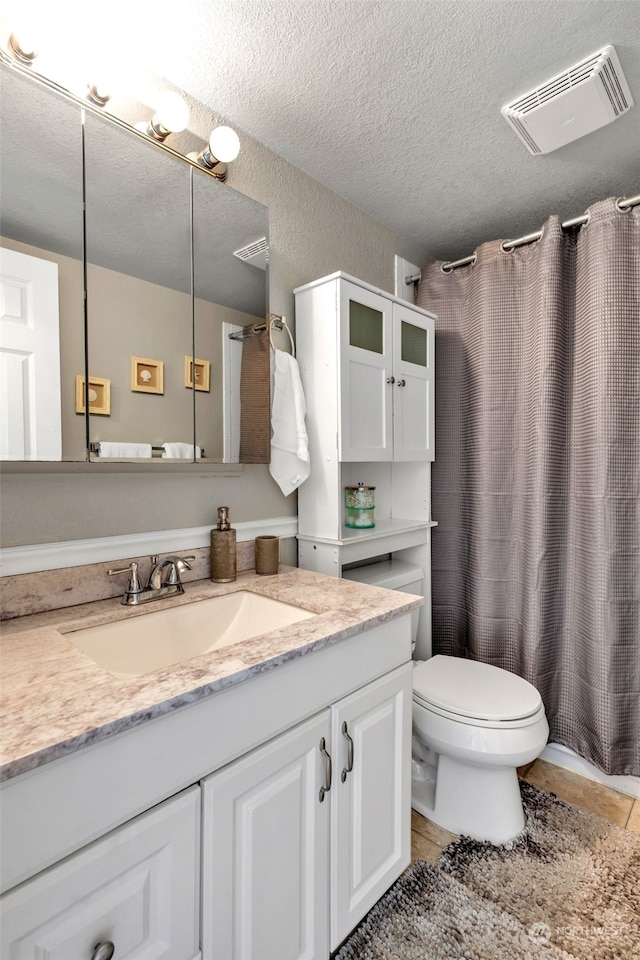 bathroom featuring vanity, walk in shower, toilet, tile patterned floors, and a textured ceiling