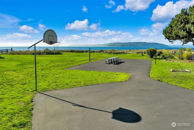 surrounding community featuring a water and mountain view, basketball court, and a lawn