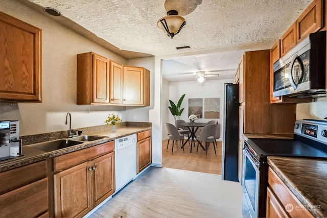 kitchen with sink, stainless steel appliances, a textured ceiling, and ceiling fan