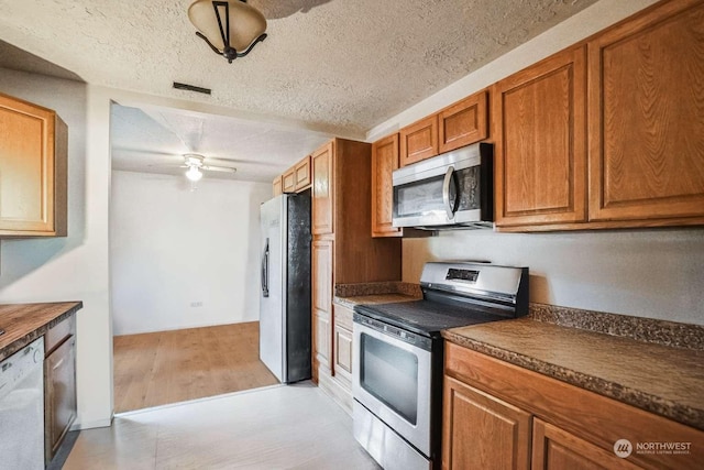 kitchen featuring ceiling fan, appliances with stainless steel finishes, light hardwood / wood-style floors, and a textured ceiling