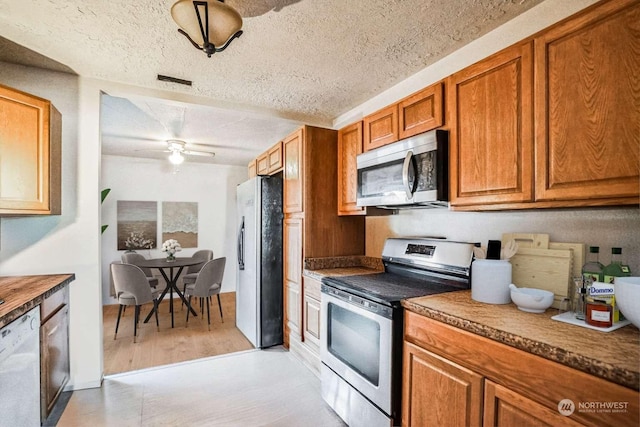 kitchen with ceiling fan, stainless steel appliances, and a textured ceiling