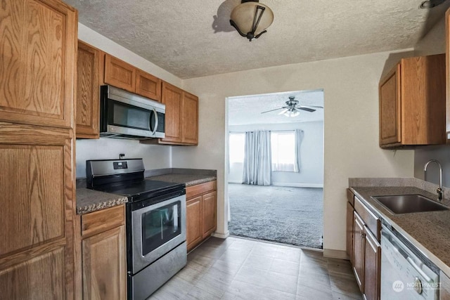 kitchen featuring appliances with stainless steel finishes, sink, light carpet, and a textured ceiling