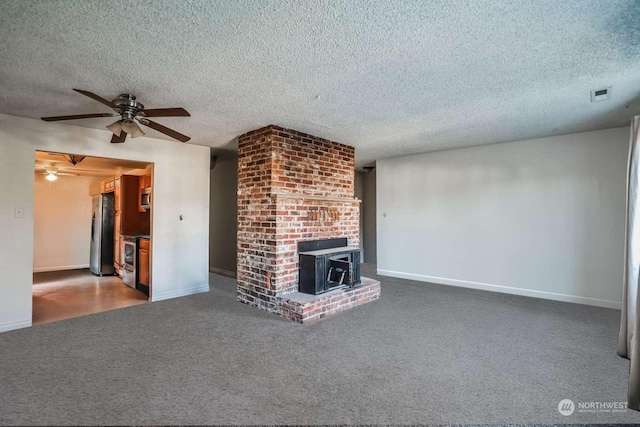 unfurnished living room featuring a textured ceiling, a wood stove, ceiling fan, and carpet