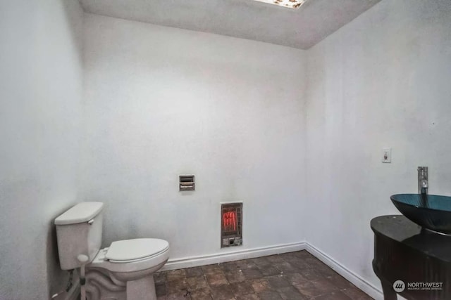 bathroom with sink, heating unit, and toilet